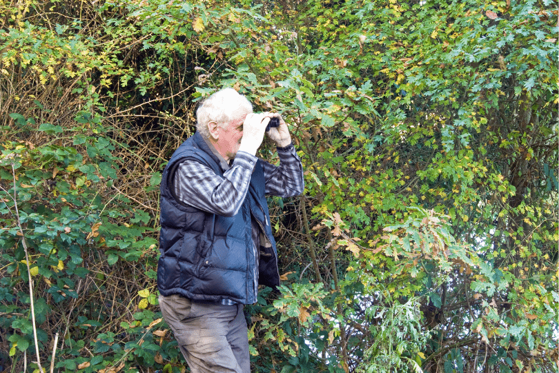 older gentleman with binoculars birdwatching